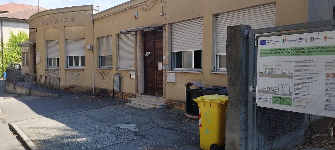 L’edificio destinato a diventare la Casa della Comunità, in via Marconi, a Chivasso. Il cartello del PNRR promette un futuro di prossimità e cura, ma il presente è fatto di crepe, silenzi e attese.
