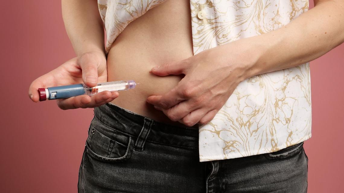 Una giovane donna con diabete usa una penna per insulina per somministrare un’iniezione, gestendo correttamente il diabete di tipo 1.