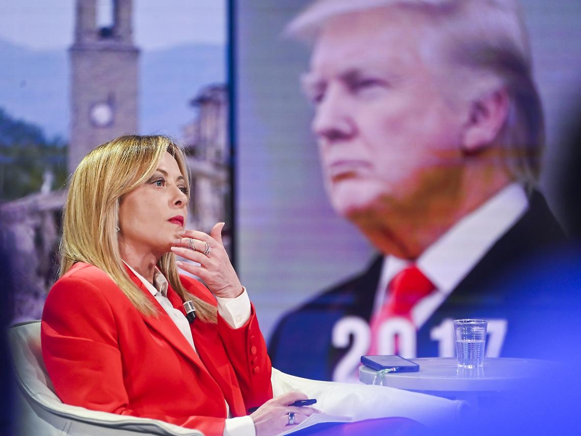 La premier Giorgia Meloni. Sullo sfondo, Donald Trump