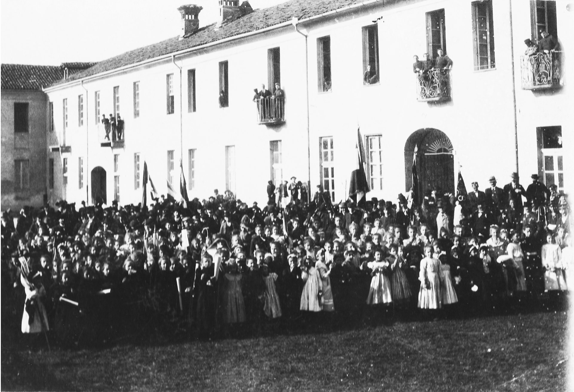 Foto di gruppo dell'inizio del secolo scorso. Sullo sfondo, l'edificio